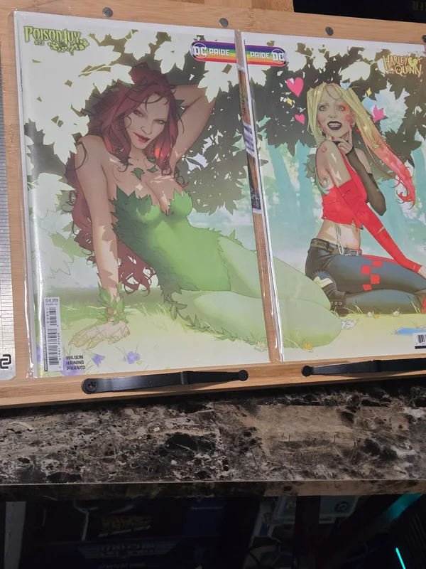 Side-by-side display of the Harley Quinn #52 and Poison Ivy #34 Pride variant covers, showcasing their connected scene.